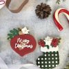 Burgundy ornament with a gold stroke and Merry Christmas written in white with a greenery accent and a poinsettia flower. The stocking is a black and white gingham pattern with royal icing poinsettias in burgundy and white.