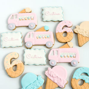 Hand-decorated pastel sugar cookies shaped like ice cream trucks, waffle cones, and number six cookies, with personalized name plaques , arranged on a light background.
