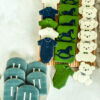 Custom baby boy sugar cookie set featuring teddy bears, rocking horses, baby bodysuits and personalized H monogram cookies in navy blue, green, & white.